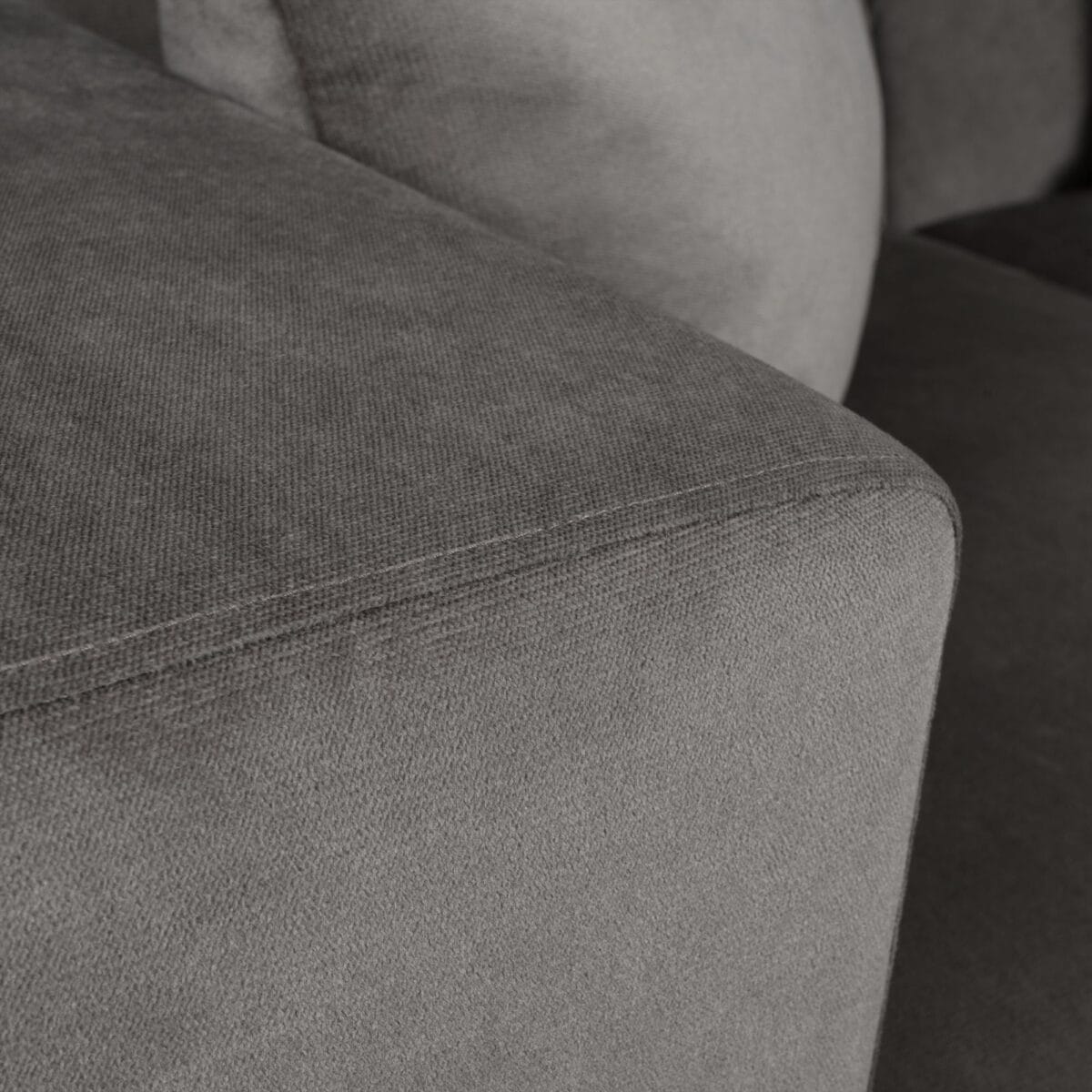 Close-up of gray textured fabric upholstery with visible seam stitching on a sofa