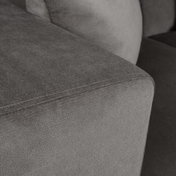 Close-up of gray textured fabric upholstery with visible seam stitching on a sofa